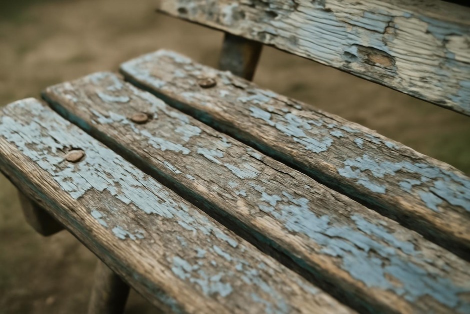 Close-up of weathered wooden bench with worn paint